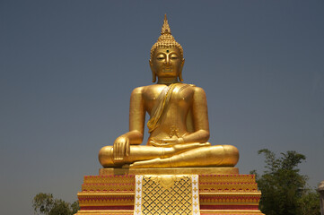 Fototapeta premium Large outdoor golden sitting Buddha image at Wat Somdet, Sangkhlaburi, a historic site in Kanchanaburi Province , Thailand. A combination of Thai-Raman and Burmese art.