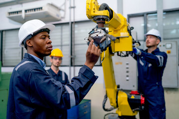 African American engineer or technician worker hold part of robotic arm and check  the function of...