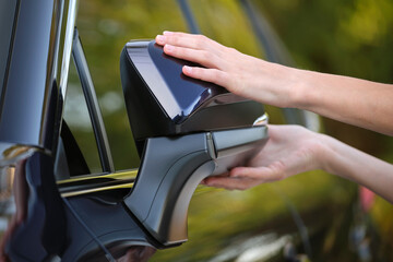 Driver hands adjusting side view mirror of a car