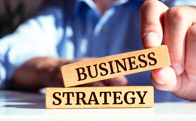 Close up on businessman holding a wooden block with Business strategy message, business concept
