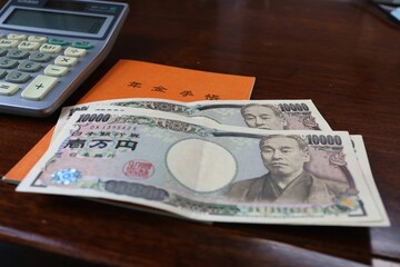 February 2023, Tokyo, Japan.Japanese pension book and cash on the table.