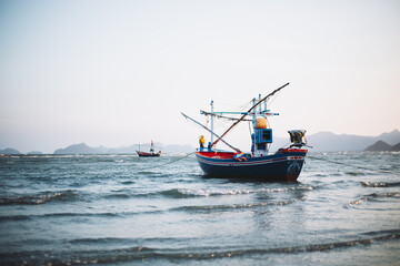 Naklejka na ściany i meble Local fishing boats stop at the beach waiting to go fishing.