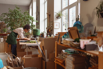 Professional woman decorator making green ikebana on tray in florist workshop