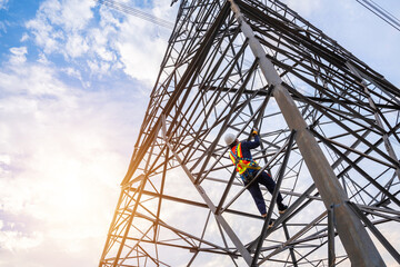 A workers wearing safety harnesses climb high-voltage pylons for inspection and maintenance at a...