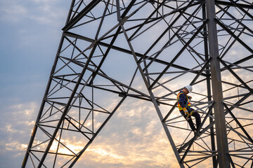 A technician or worker are using safety harnesses to climb high-voltage pylons for inspection and...