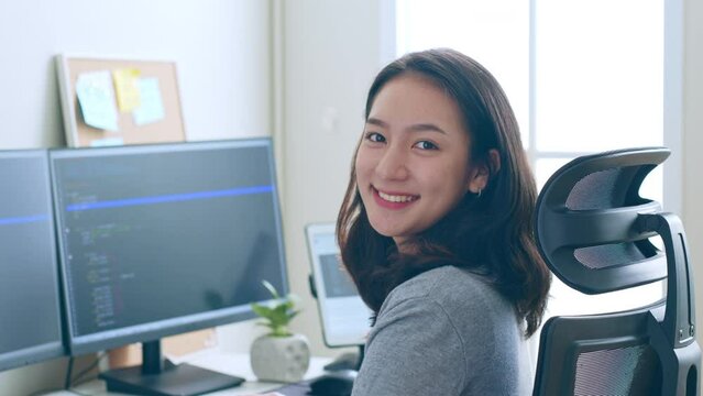 Portrait young Asian woman developer programmer, software engineer, IT support, look at camera and smile enjoy working at office