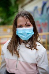 Little girl with surgical mask in a public park.