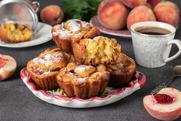 Homemade muffins with peaches sprinkled powdered sugar on plate on gray background, Close-up
