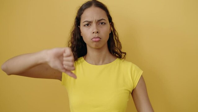 Young african american woman doing negative gesture with thumbs down over isolated yellow background