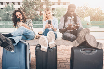 A group of young friends waiting relaxed and carefree at train station while watching the travel rout on smartphone. 
Travel, photography and lifestyle concept