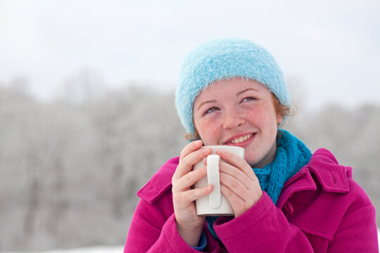 Teenage girl enjoying a Hot Chocolate outside in the snow in winter,UK.