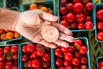 Customer holding tokens against cherry tomatoes