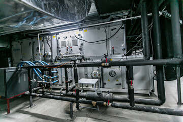 Huge industrial water pump and air handling unit in the ventilation plant room with ductworks and insulated pipelines