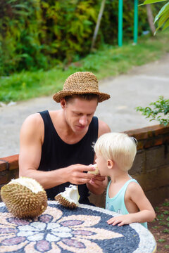 Father and son eating durian at table, Kintamani, Bali, Indonesia