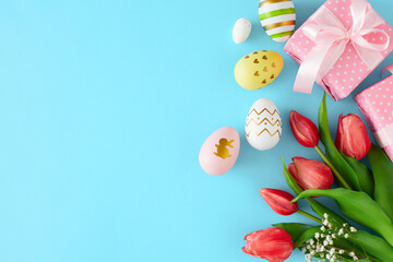 Fototapeta na wymiar Easter concept. Flat lay photo of color eggs, gift boxes and tulips flowers on pastel blue background with copyspace. Easter holiday idea.