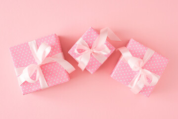 Spring gift concept. Flat lay photo of pink present boxes with silk ribbon bows on pastel pink background.