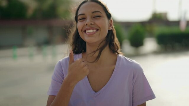 Young african american woman smiling confident doing ok sign with thumb up at street