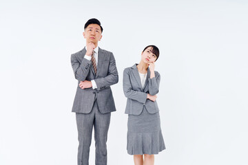 疑問を感じるポーズをするスーツ姿の男女