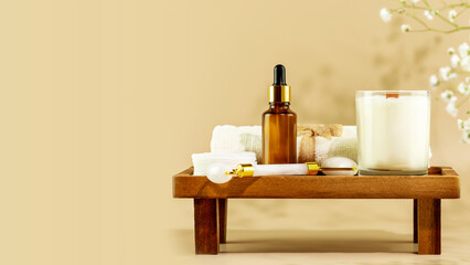Eco friendly spa relax composition with serum, face roller, towel and candle on wooden podium on beige background with copy space. Wellness and skin care treatment. Concept of me time and self care