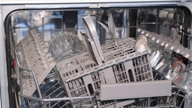 A woman arranges dishes in the dishwasher for automatic washing, to make household chores easier