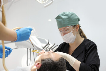 cheerful female dentist holding drill and smiling near patient . High quality photo