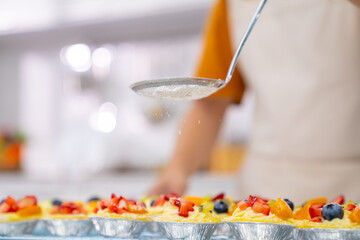 Asian man bakery shop owner making cake and bakery for sell in the kitchen. Bakery chef making fruit tart with cream cheese on kitchen counter. Small business entrepreneur cafe and restaurant concept.
