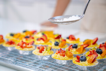 Asian man bakery shop owner making cake and bakery for sell in the kitchen. Bakery chef making fruit tart with cream cheese on kitchen counter. Small business entrepreneur cafe and restaurant concept.