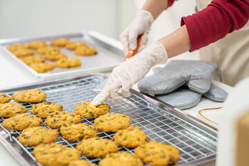 Asian woman bakery shop owner preparing customer order cookie in delivery box on kitchen counter. Woman bakery chef making bakery in the kitchen. Small business entrepreneur and food delivery concept.