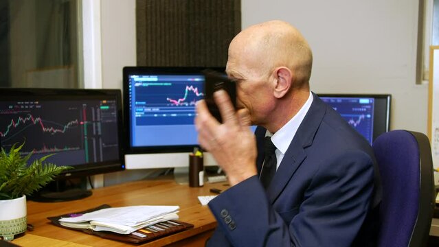 A mature business man stock broker making a phone call in his trading office