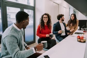Fototapeta premium Young multiracial couples enjoying conversation at the office kitchen while taking a break from work