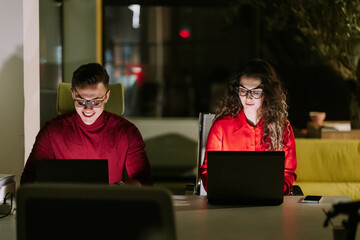 Handsome smiley male person working together late at night with his female partner at modern co...