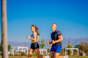 A side view photo of male and female friends running