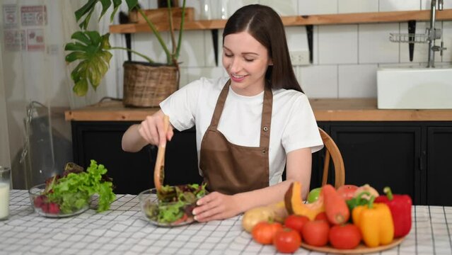 cheerful woman holding bowl with fresh mixed salad at home..