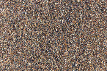 Beautiful horizontal texture of yellow sand with waves pebbles and shells is in the photo