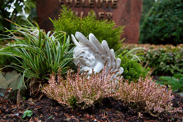 Kleiner Engel zwischen grünen Pflanzen auf einem Friedhof in Velbert