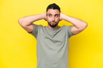 Fototapeta na wymiar Young Arab handsome man isolated on yellow background frustrated and covering ears