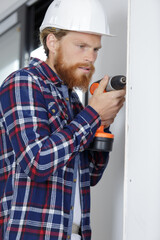 man with hard hat on construction site using drill