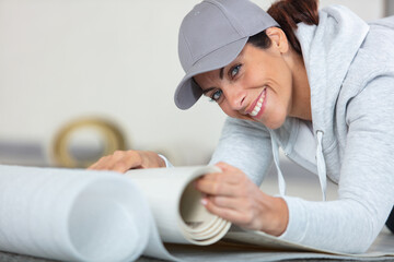 smiling female worker with a roll of linoleum