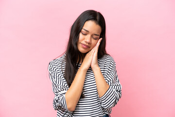 Young Colombian woman isolated on pink background making sleep gesture in dorable expression