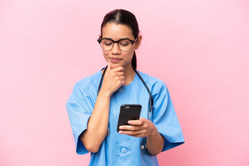 Young nurse Colombian woman isolated on pink background thinking and sending a message