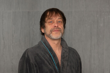 Portrait of an elderly man 45-50 years old with a gray beard in a bathrobe.