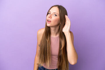 Young Lithuanian woman isolated on purple background listening to something by putting hand on the ear