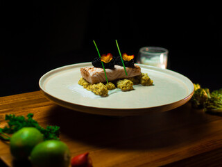 Fish on a white plate served with vegetables and mash potatoes on a dark background