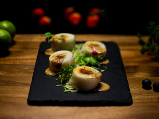fried fish dish served with green vegetables on a dark and white plate. Fine dining seafood served on a wooden table and a dark background. International restaurant menu.