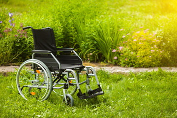 Empty wheelchair in the garden or in the park. Wheelchair in the grass in the garden.