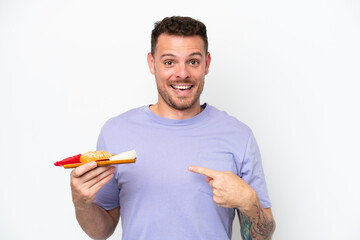 Young caucasian man holding sashimi isolated on white background with surprise facial expression