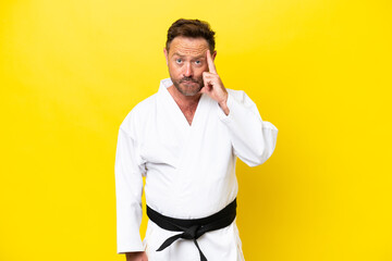 Middle age caucasian man doing karate isolated on yellow background thinking an idea © luismolinero