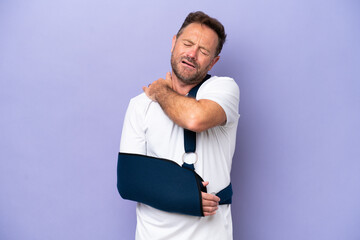 Middle age caucasian man with broken arm and wearing a sling isolated on purple background...