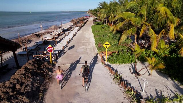 Couple Riding bikes through island Holbox Mexico. Cruising through Beautiful coastline in popular holiday destination.