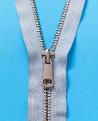 Light zipper close up on a blue background. Top view. © Tanya